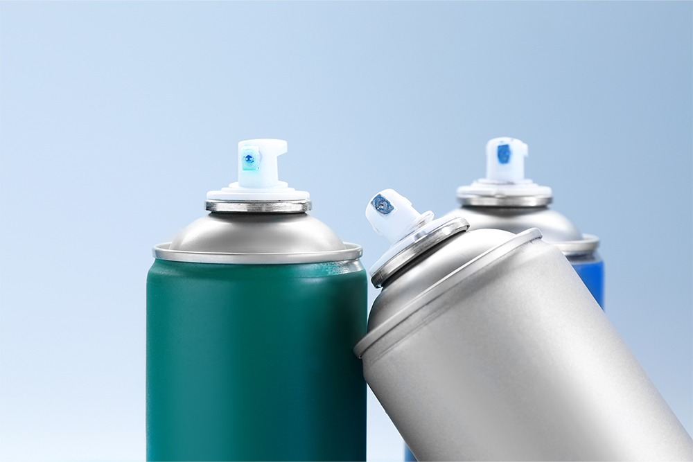 Half slider of three aerosol cans on a light blue background