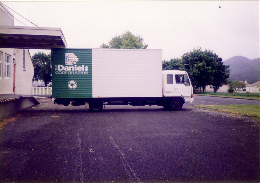 Vintage Daniels Corporation collection truck parked outside a facility.